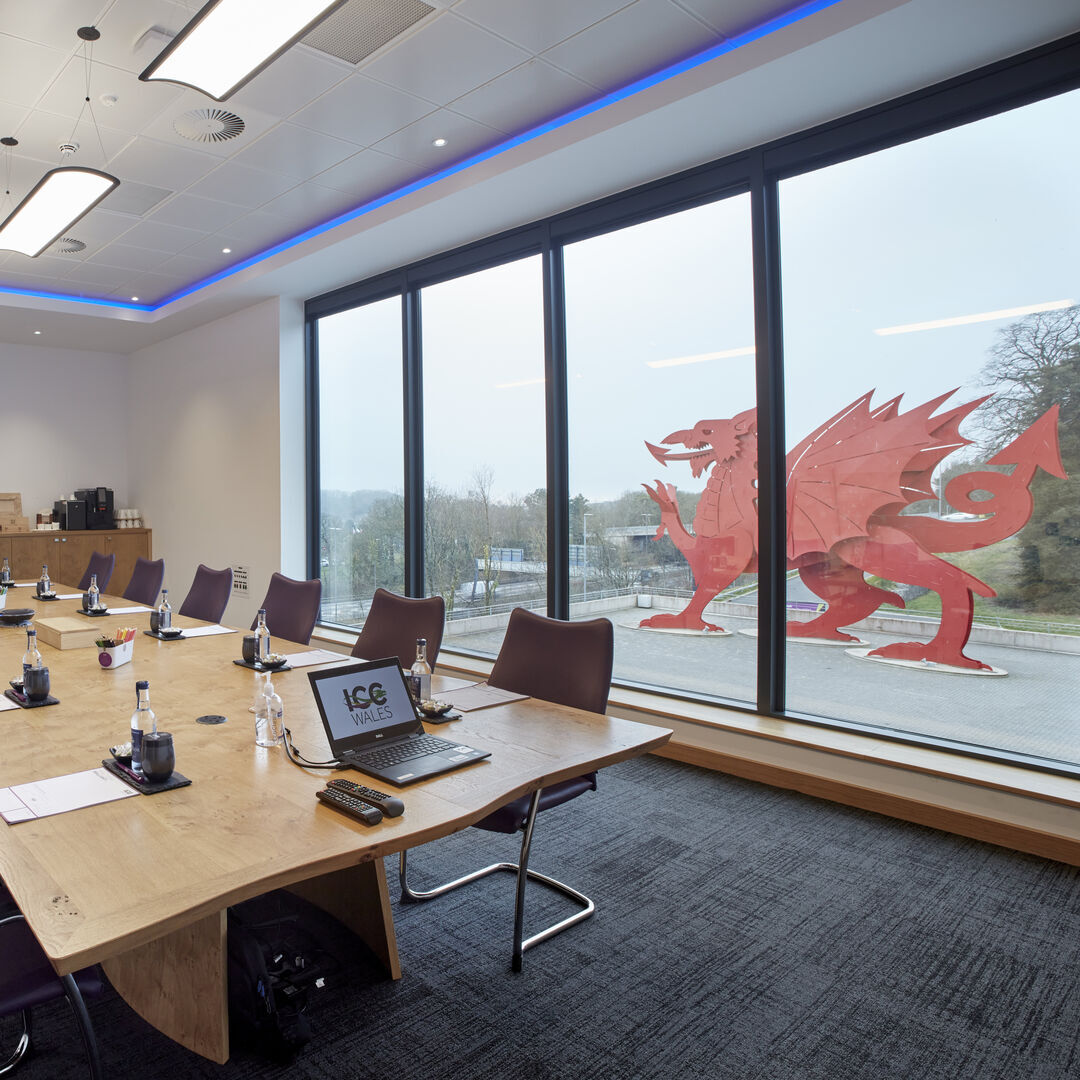 A meeting room at ICC Wales, with purple chairs around a rectangular table and views of the ICC Wales dragon