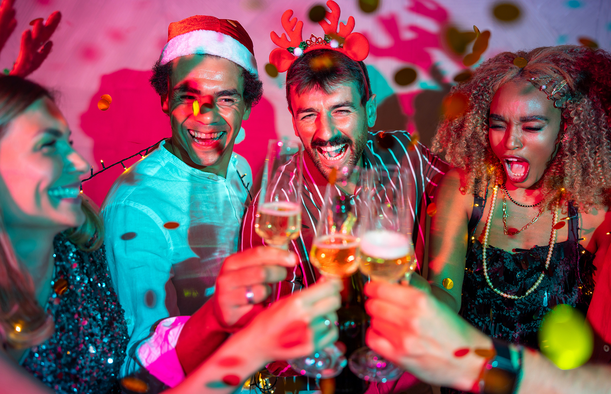 Group of cheerful young friends having fun making a toast and drinking champagne at New Year party midnight countdown