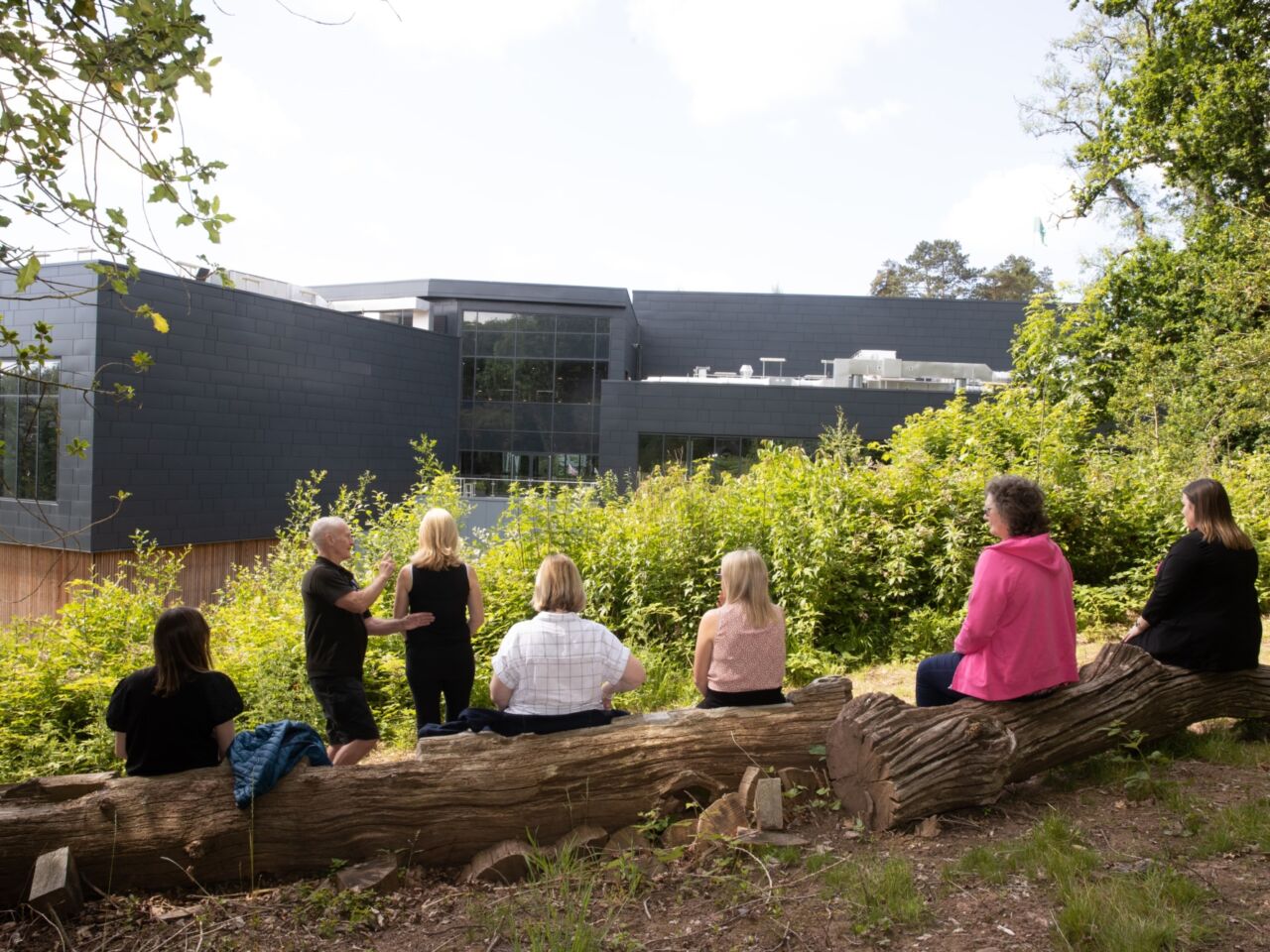 Guests sat outside on a log, exploring the outdoor space at ICC Wales